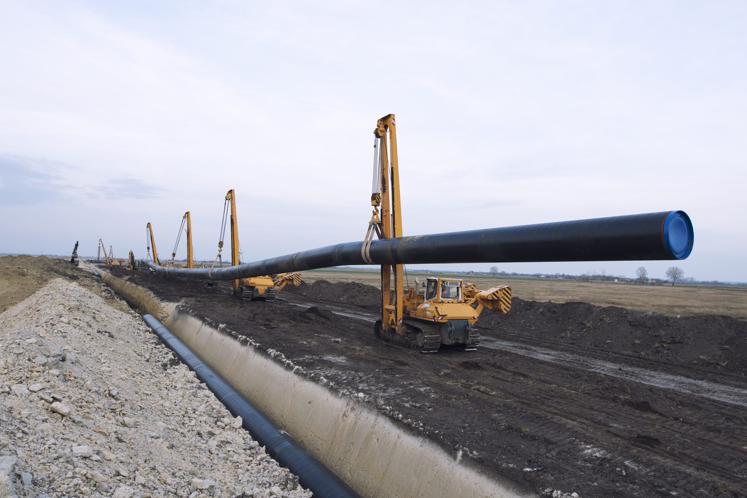 heavy duty construction machines carrying placing gas pipe into ground scaled